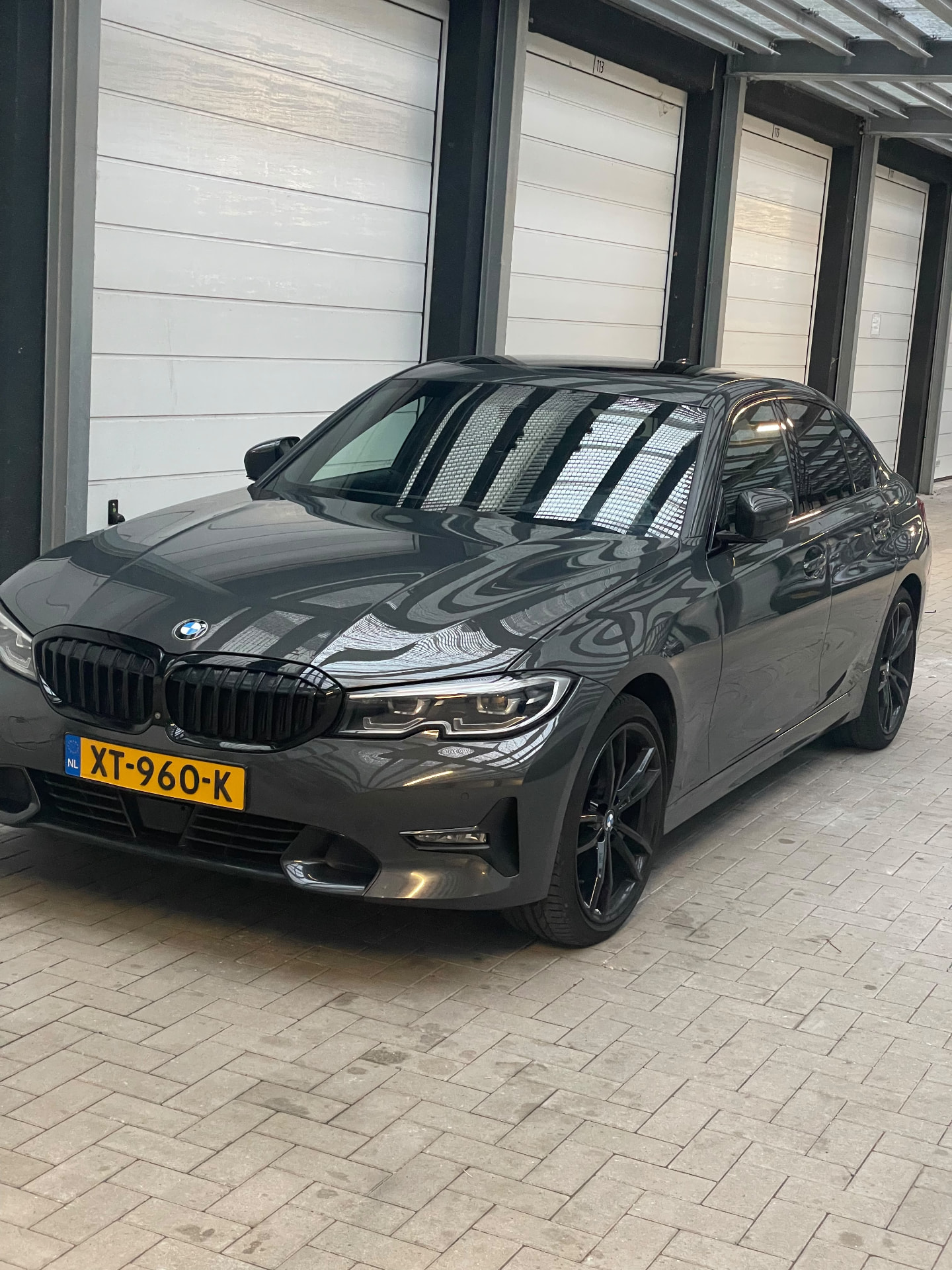 BMW Serie 3 gris antracita de tres cuartos con reflejos nítidos en el capó