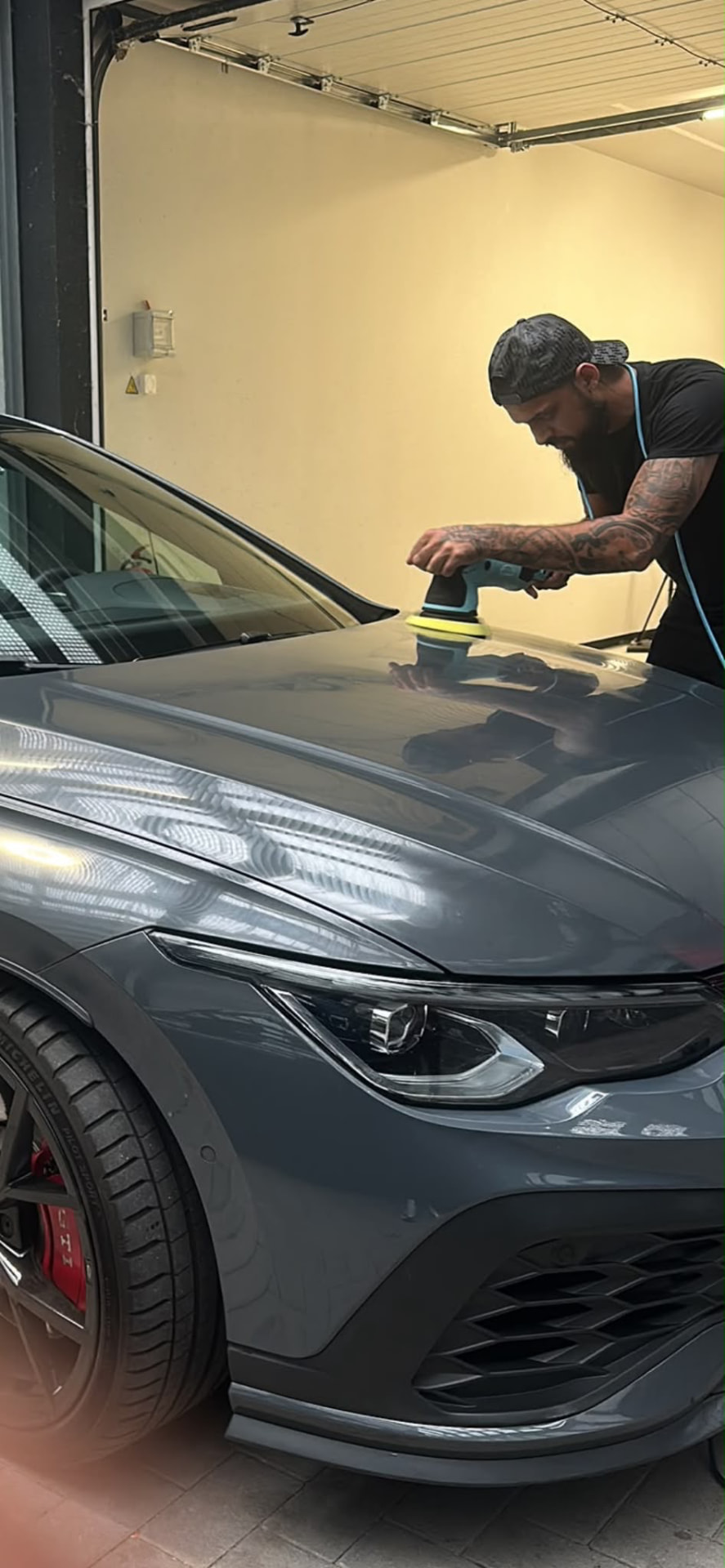 Volkswagen Golf GTI gris oscuro mientras se pule el capó a máquina