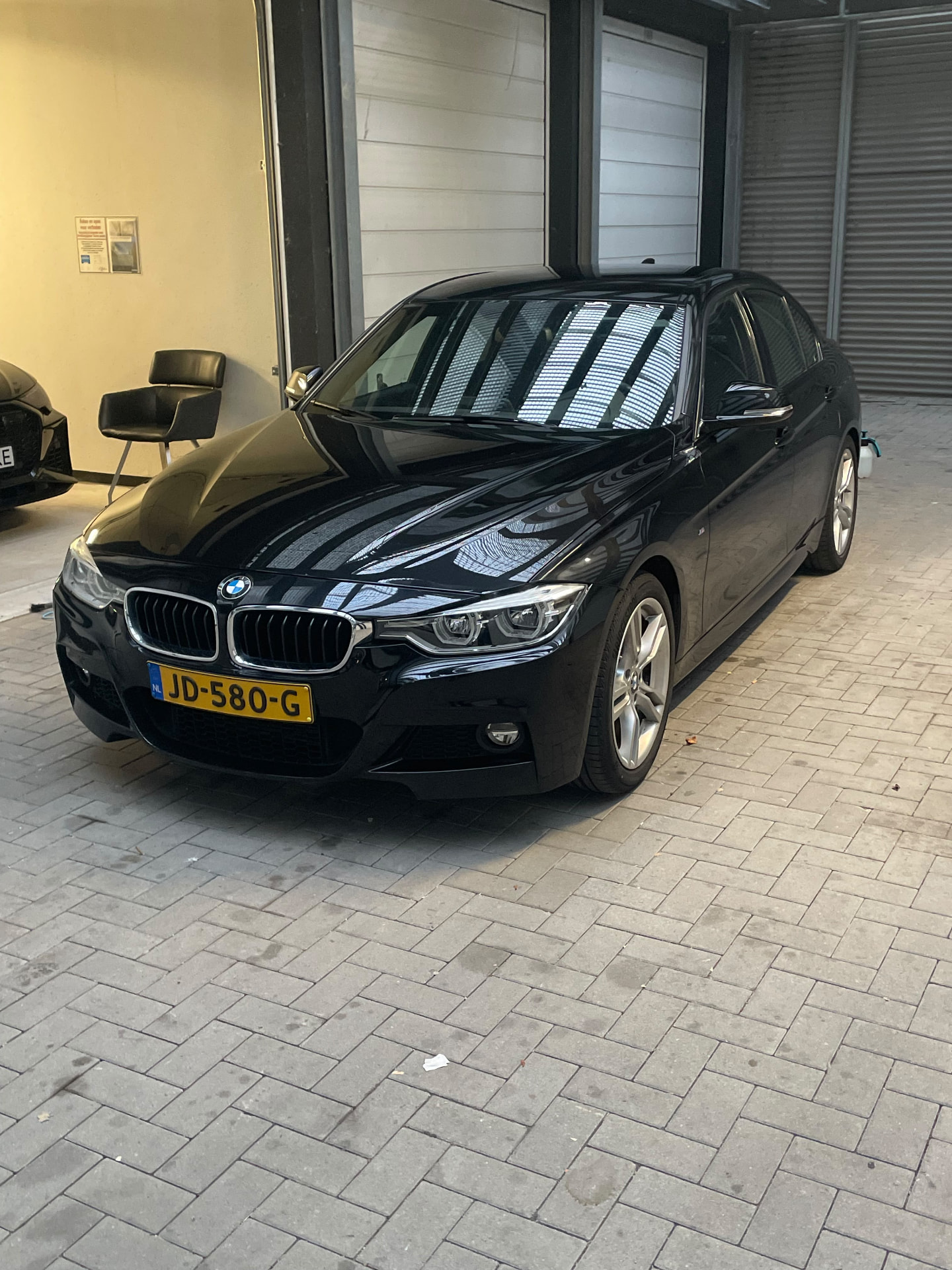 BMW Serie 3 negro de frente dentro de la nave, con reflejos del techo