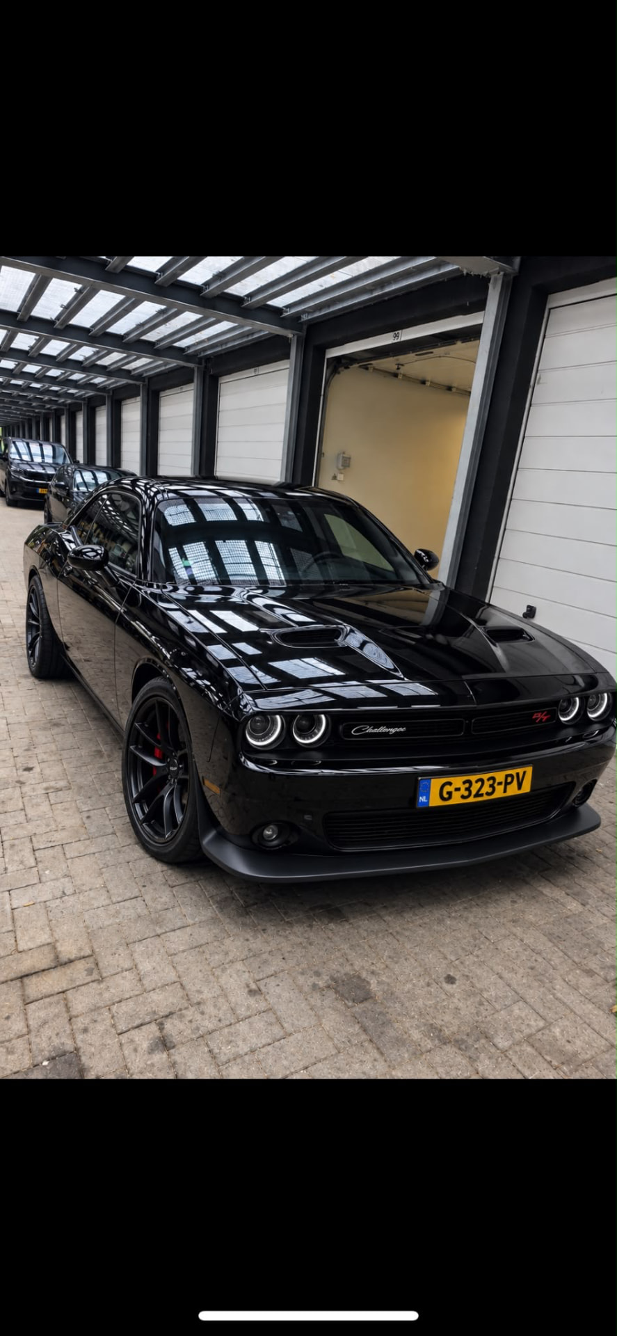 Dodge Challenger negro de frente bajo la pérgola, con brillo espejo